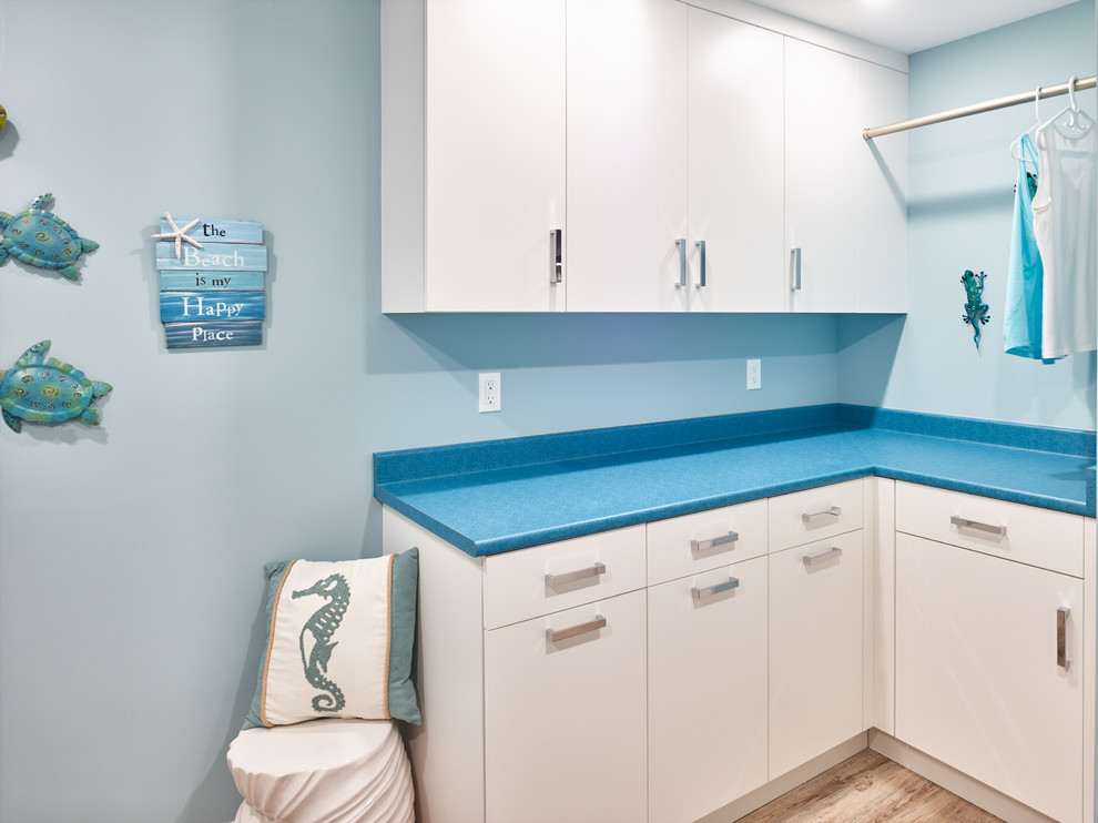 Esempio di una sala lavanderia chic di medie dimensioni con lavello da incasso, ante lisce, ante bianche, top in laminato, pareti blu, pavimento in legno massello medio, lavatrice e asciugatrice affiancate, pavimento marrone e top blu