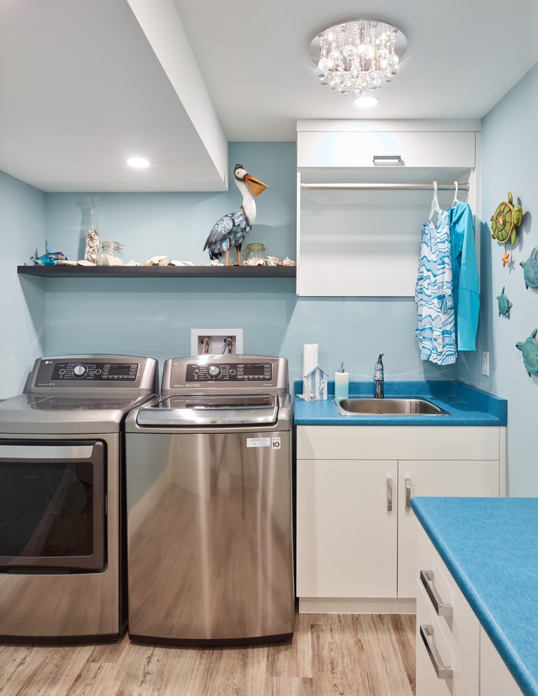Mittelgroße Klassische Waschküche in L-Form mit Einbauwaschbecken, flächenbündigen Schrankfronten, weißen Schränken, Laminat-Arbeitsplatte, blauer Wandfarbe, braunem Holzboden, Waschmaschine und Trockner nebeneinander, braunem Boden und blauer Arbeitsplatte in Vancouver