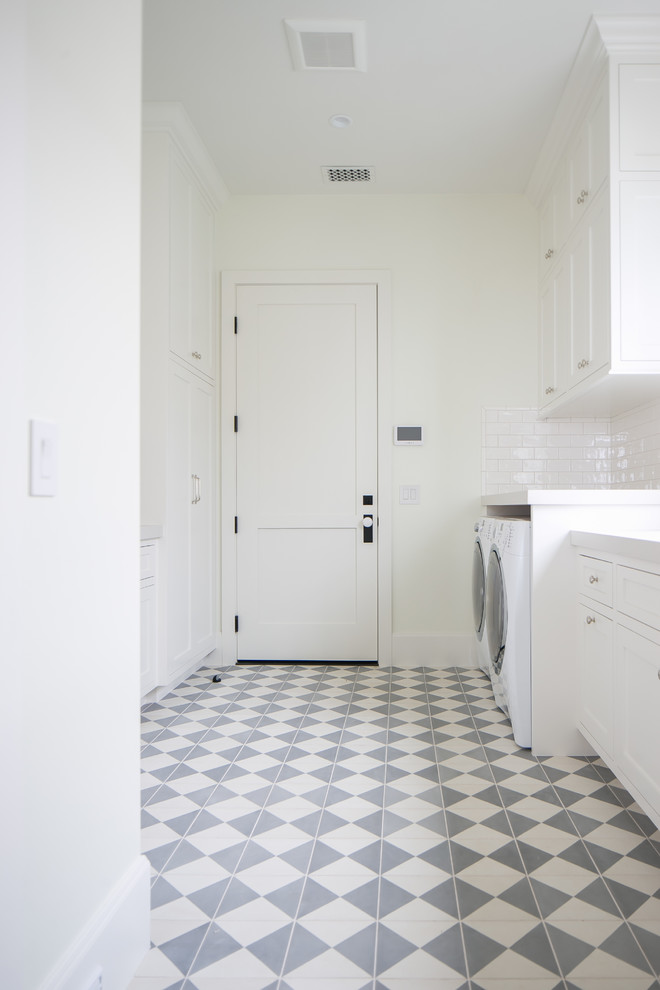 Idéer för att renovera en stor vintage linjär tvättstuga enbart för tvätt, med skåp i shakerstil, vita skåp, vita väggar, klinkergolv i porslin, en tvättmaskin och torktumlare bredvid varandra och flerfärgat golv