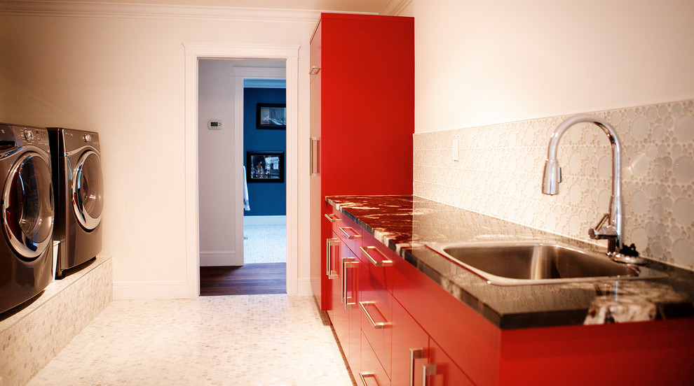 Example of a minimalist galley ceramic tile dedicated laundry room design in Vancouver with an undermount sink, flat-panel cabinets, red cabinets, granite countertops, white walls and a side-by-side washer/dryer