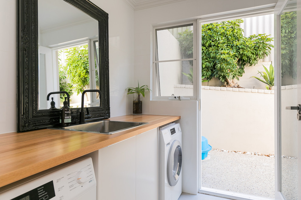 Einzeilige Moderne Waschküche mit Einbauwaschbecken, flächenbündigen Schrankfronten, weißen Schränken, Arbeitsplatte aus Holz, weißer Wandfarbe und brauner Arbeitsplatte in Perth