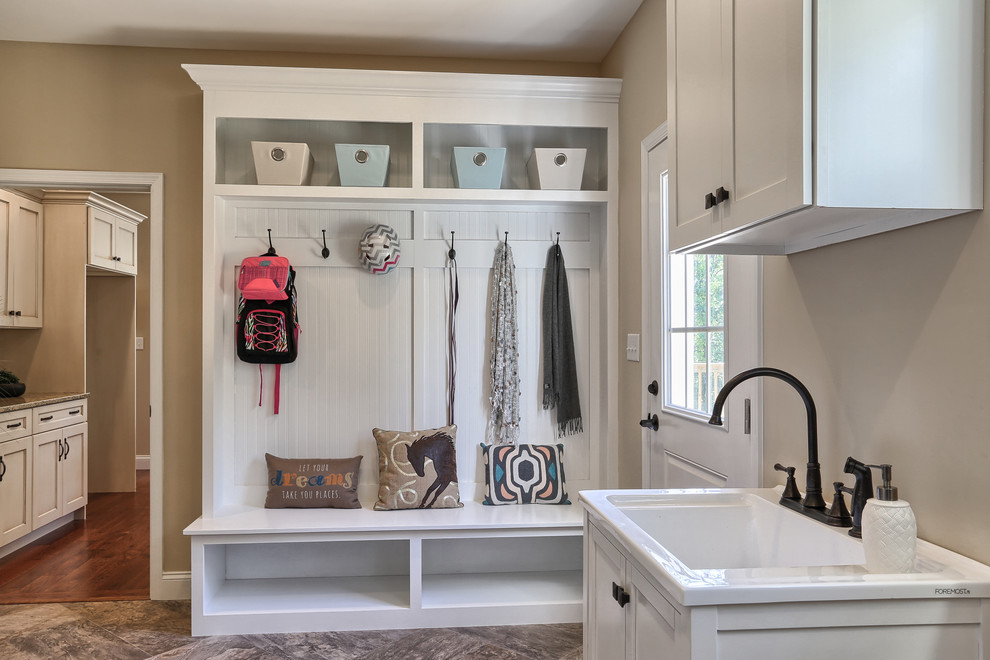 Diseño de cuarto de lavado lineal tradicional renovado grande con fregadero integrado, armarios con paneles empotrados, puertas de armario blancas y suelo vinílico