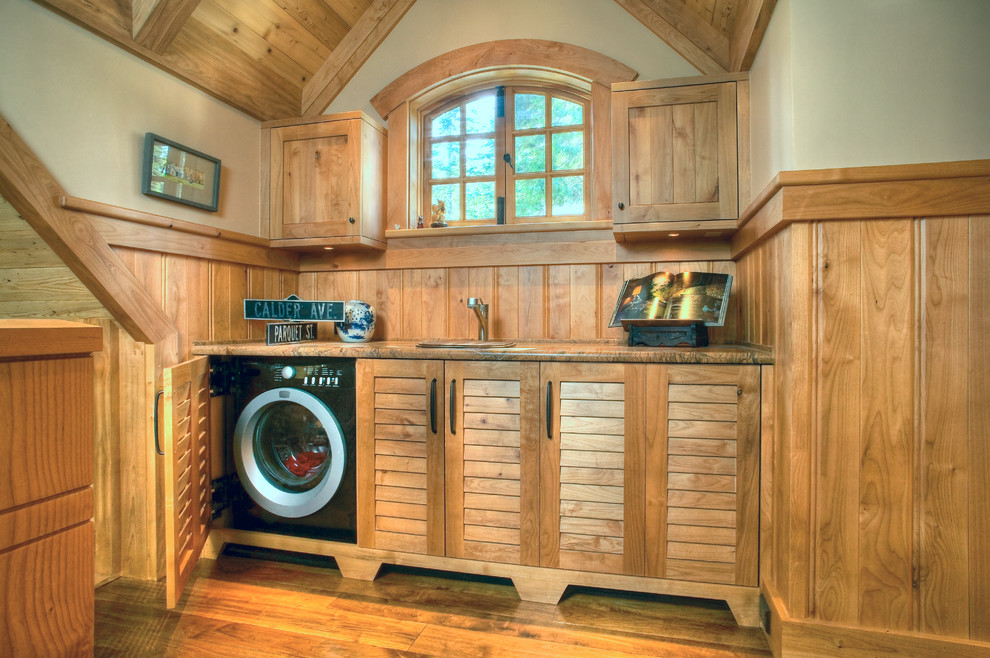 Immagine di una lavanderia classica con ante a persiana, ante in legno scuro, pareti beige e pavimento in legno massello medio