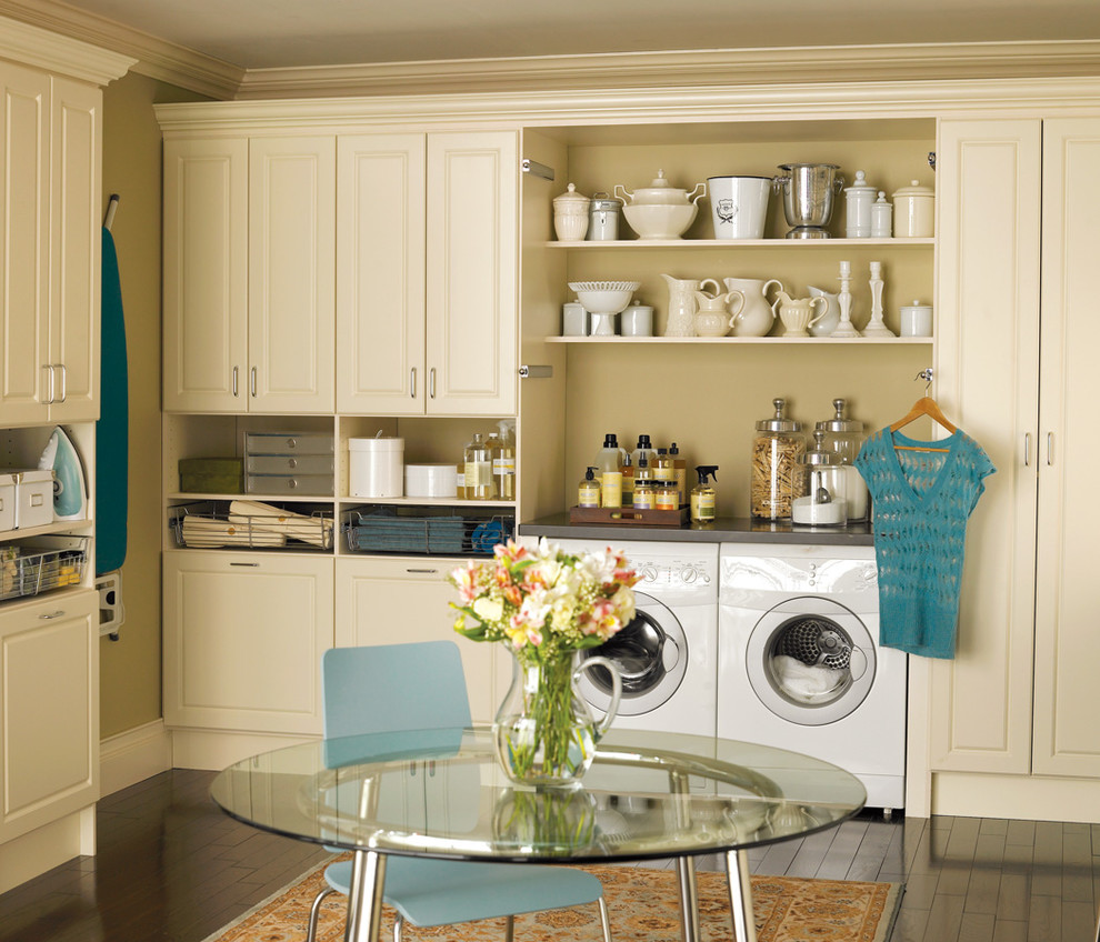Foto di una grande lavanderia multiuso chic con ante con bugna sagomata, ante beige, top in cemento, pareti beige, parquet scuro, lavatrice e asciugatrice affiancate e pavimento marrone