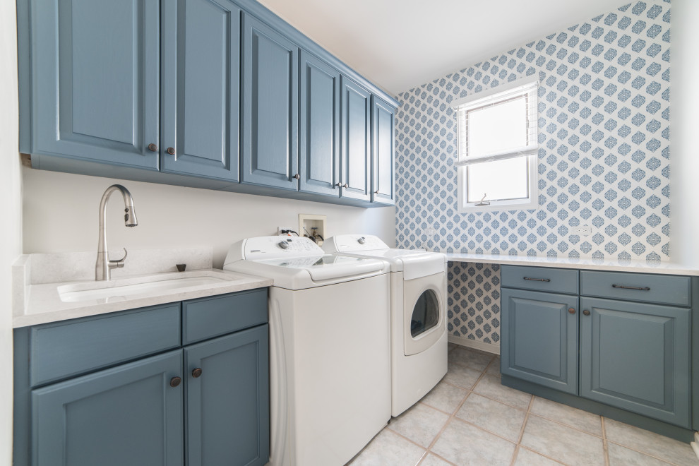 Mittelgroße Klassische Waschküche in L-Form mit Unterbauwaschbecken, blauen Schränken, Waschmaschine und Trockner nebeneinander und Tapetenwänden in Chicago