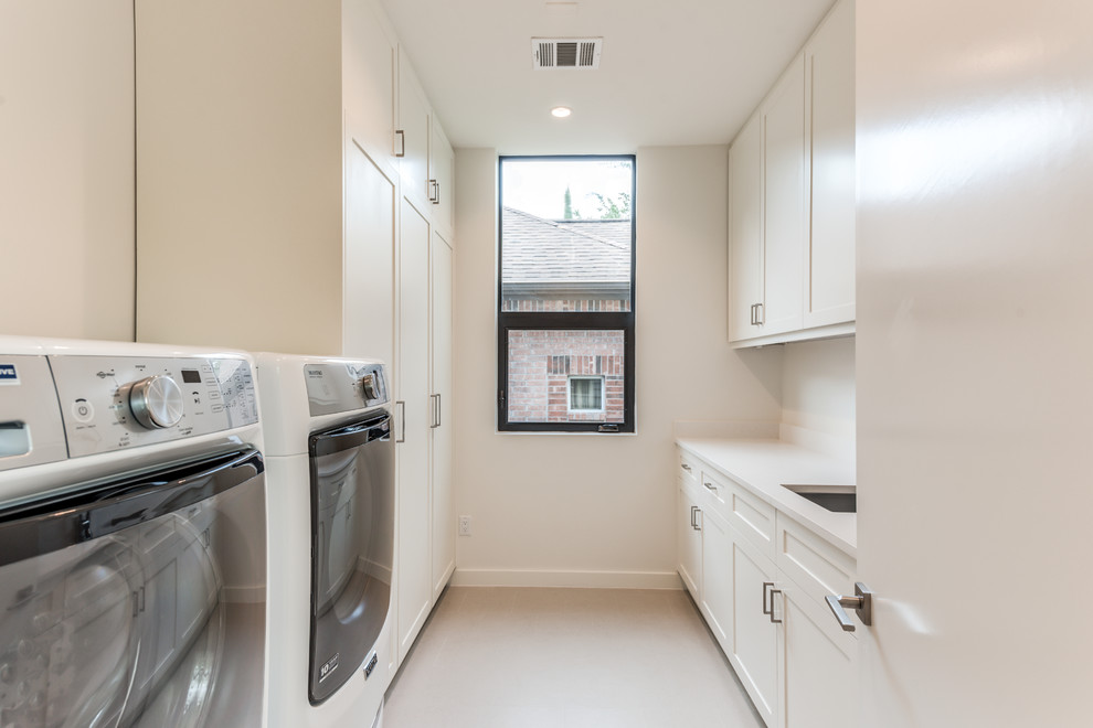 Photo of a medium sized contemporary galley separated utility room in Houston with a submerged sink, shaker cabinets, white cabinets, composite countertops, white walls, porcelain flooring, a side by side washer and dryer, grey floors and white worktops.