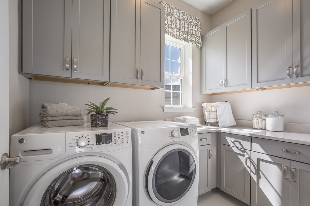 Idee per una sala lavanderia classica con ante grigie, lavatrice e asciugatrice affiancate, top bianco, ante con riquadro incassato, pavimento beige e pareti grigie