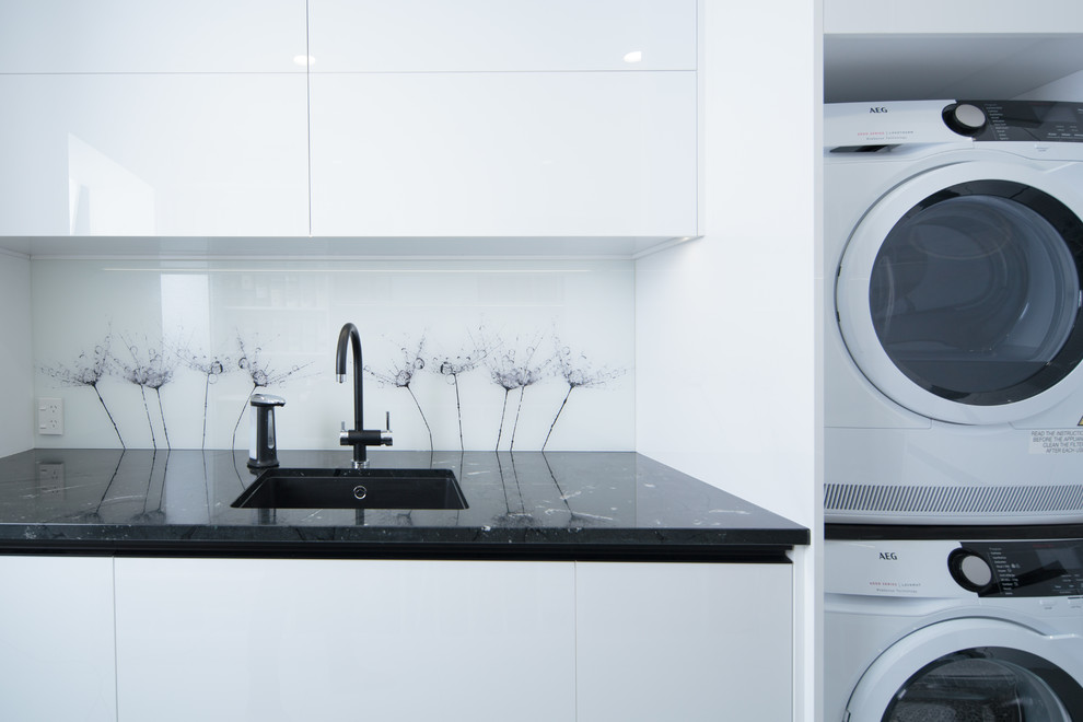 Medium sized modern u-shaped utility room in Other with a single-bowl sink, white cabinets, granite worktops, ceramic flooring, white floors and black worktops.