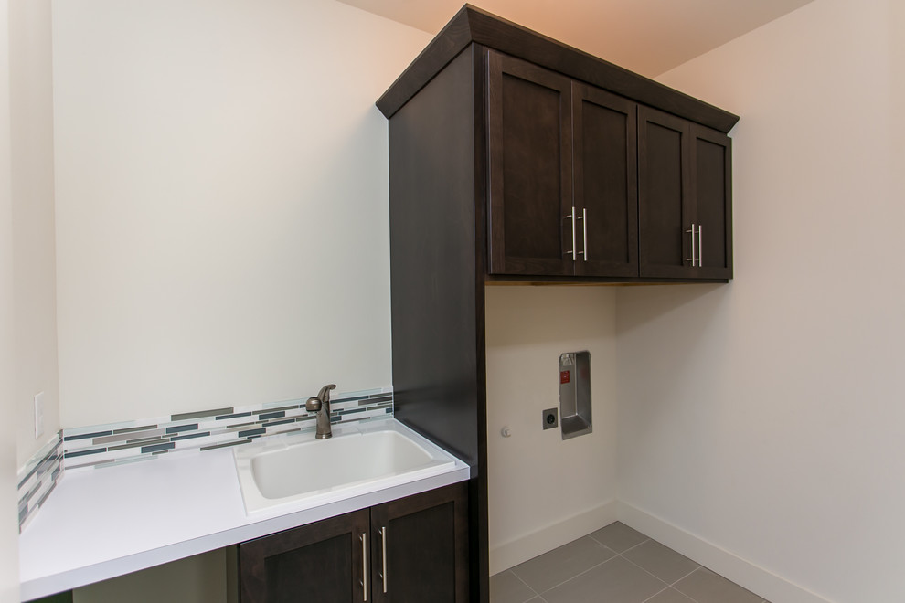 Example of a small minimalist single-wall porcelain tile and gray floor dedicated laundry room design in Seattle with a drop-in sink, shaker cabinets, dark wood cabinets, laminate countertops, white walls and a side-by-side washer/dryer