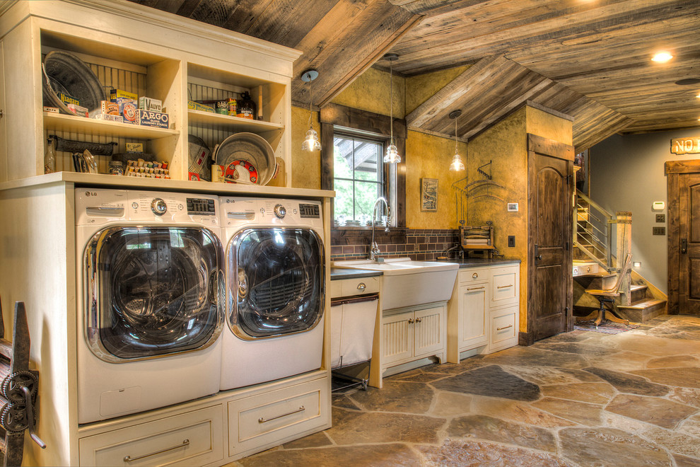 This is an example of a large rustic galley separated utility room in Minneapolis with a double-bowl sink, beaded cabinets, white cabinets, granite worktops, yellow walls, slate flooring, a side by side washer and dryer, multi-coloured floors and black worktops.