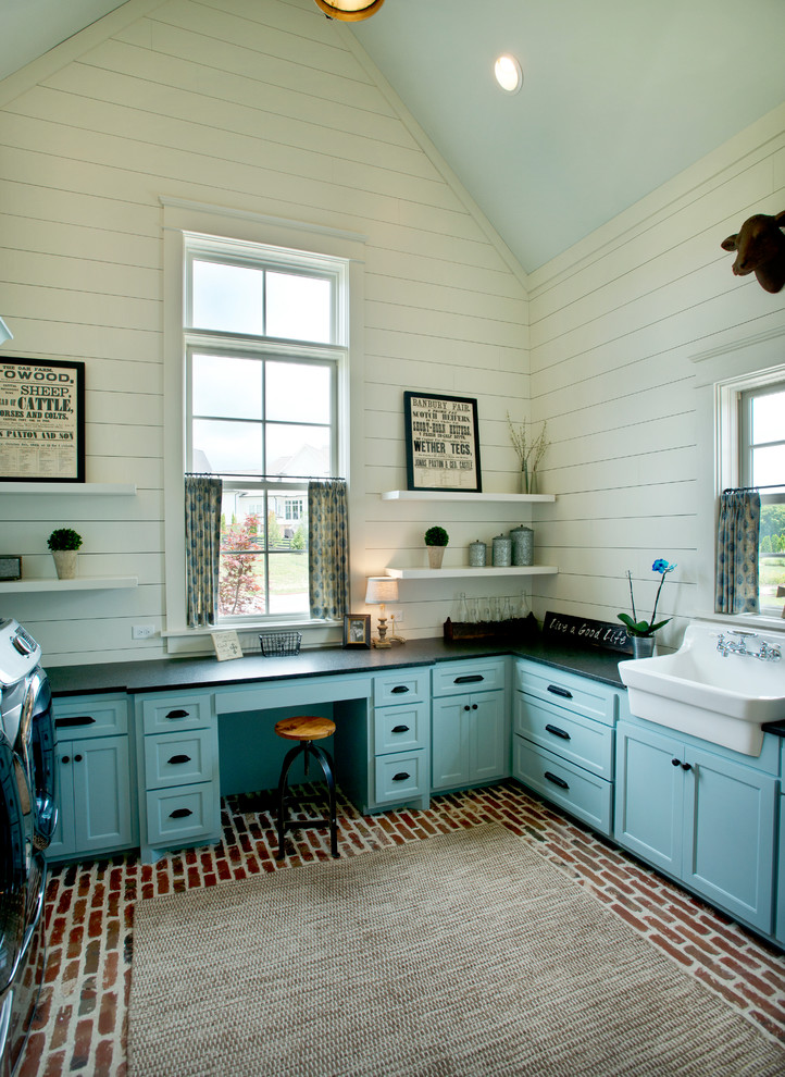 Design ideas for a farmhouse u-shaped utility room in Nashville with a belfast sink, shaker cabinets, blue cabinets, soapstone worktops, white walls, brick flooring and a side by side washer and dryer.