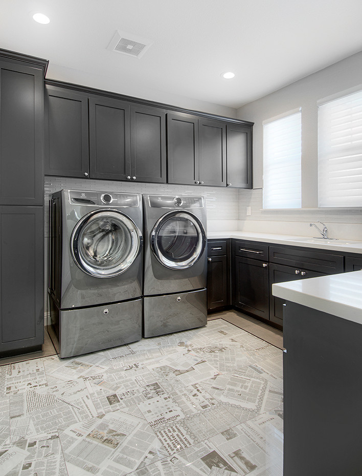 Klassisk inredning av en u-formad tvättstuga, med skåp i shakerstil, svarta skåp, en tvättmaskin och torktumlare bredvid varandra, en undermonterad diskho och grå väggar