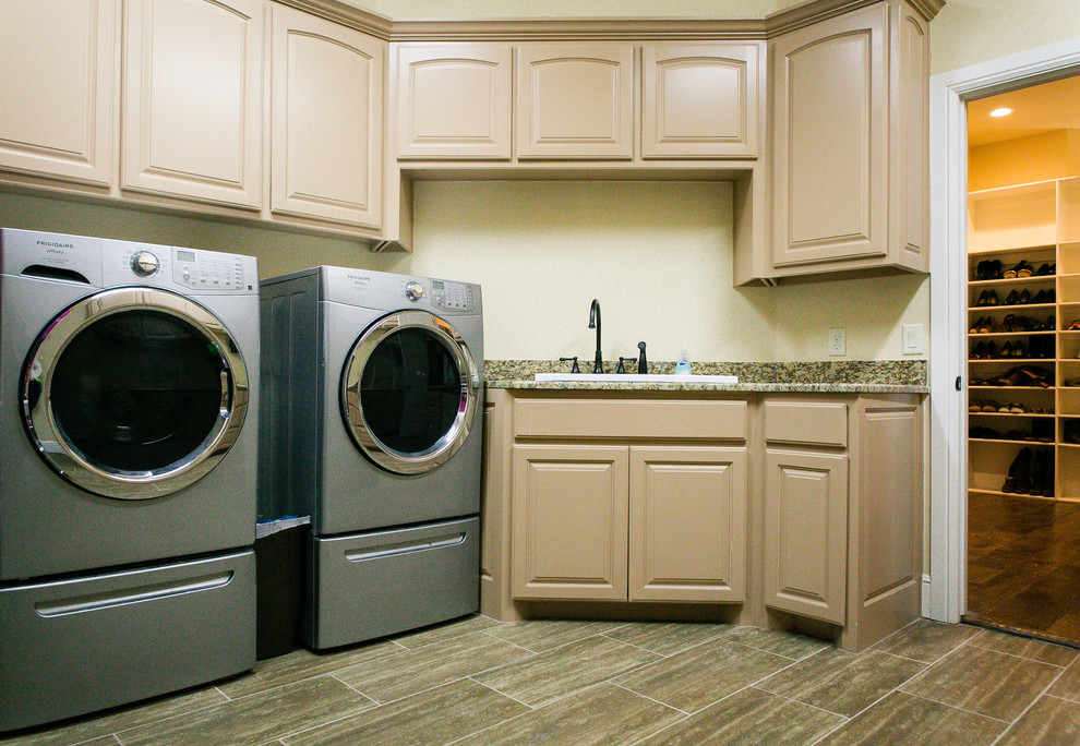 Inspiration för mellanstora klassiska l-formade tvättstugor enbart för tvätt, med en allbänk, luckor med upphöjd panel, beige skåp, granitbänkskiva, vita väggar, klinkergolv i porslin, en tvättmaskin och torktumlare bredvid varandra och flerfärgat golv
