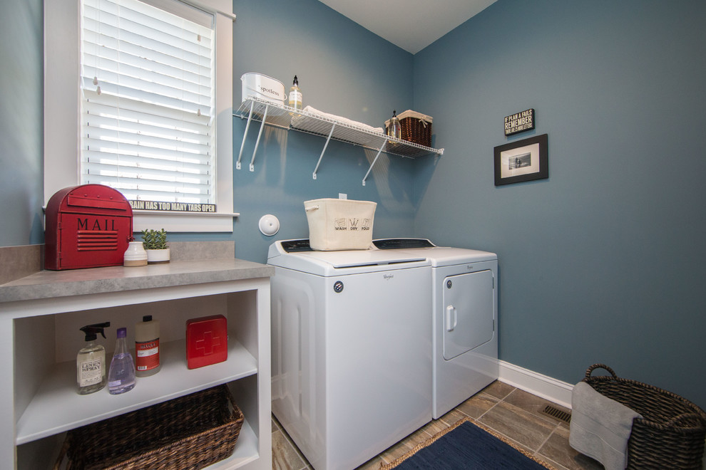 Inspiration för mellanstora amerikanska linjära flerfärgat tvättstugor enbart för tvätt, med öppna hyllor, vita skåp, laminatbänkskiva, blå väggar, klinkergolv i keramik, en tvättmaskin och torktumlare bredvid varandra och flerfärgat golv