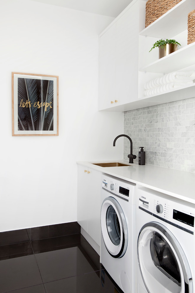 Zweizeiliger Moderner Hauswirtschaftsraum mit Einbauwaschbecken, flächenbündigen Schrankfronten, weißen Schränken, Quarzwerkstein-Arbeitsplatte, weißer Wandfarbe und Waschmaschine und Trockner nebeneinander in Melbourne