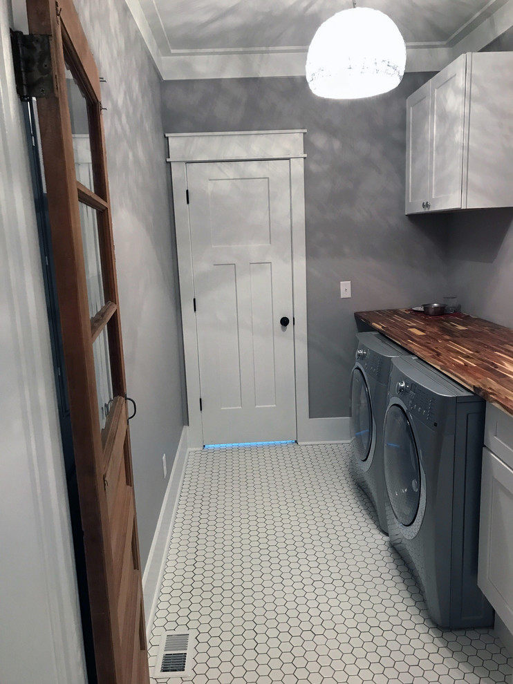 Landhaus Waschküche mit grauer Wandfarbe und Waschmaschine und Trockner nebeneinander in Sonstige