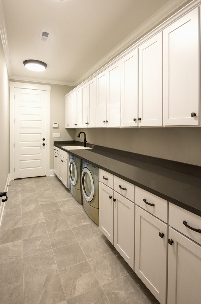 Immagine di una sala lavanderia classica con ante in stile shaker, ante beige, pareti beige, pavimento con piastrelle in ceramica, lavatrice e asciugatrice affiancate e pavimento beige