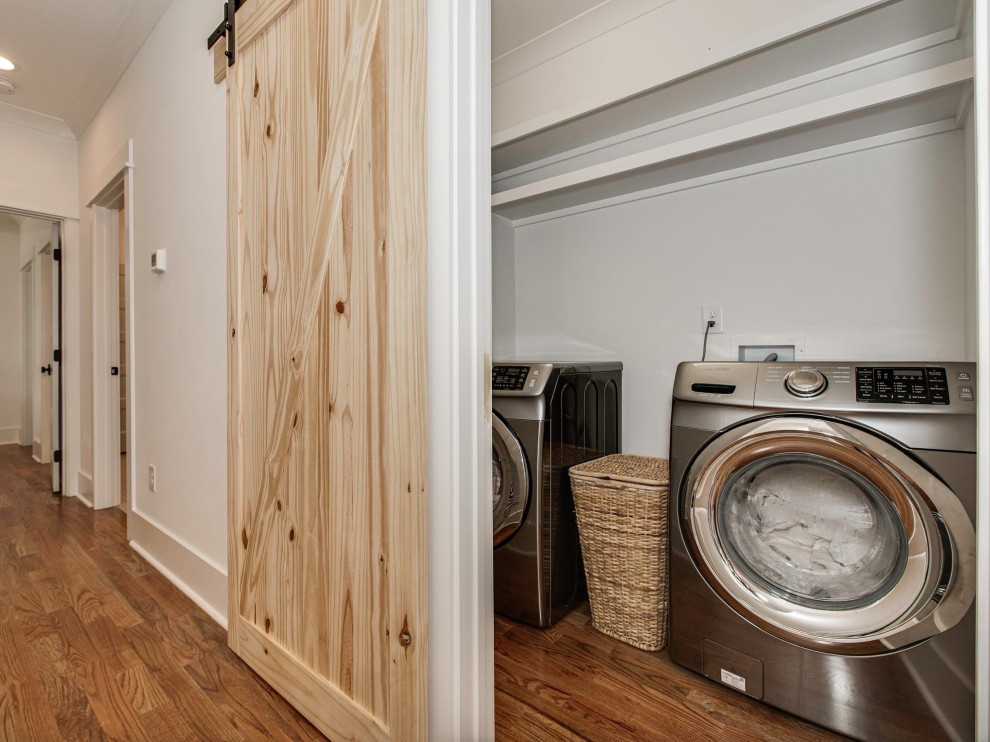 Inspiration for a small craftsman single-wall medium tone wood floor and brown floor laundry closet remodel in Charlotte with white walls and a side-by-side washer/dryer