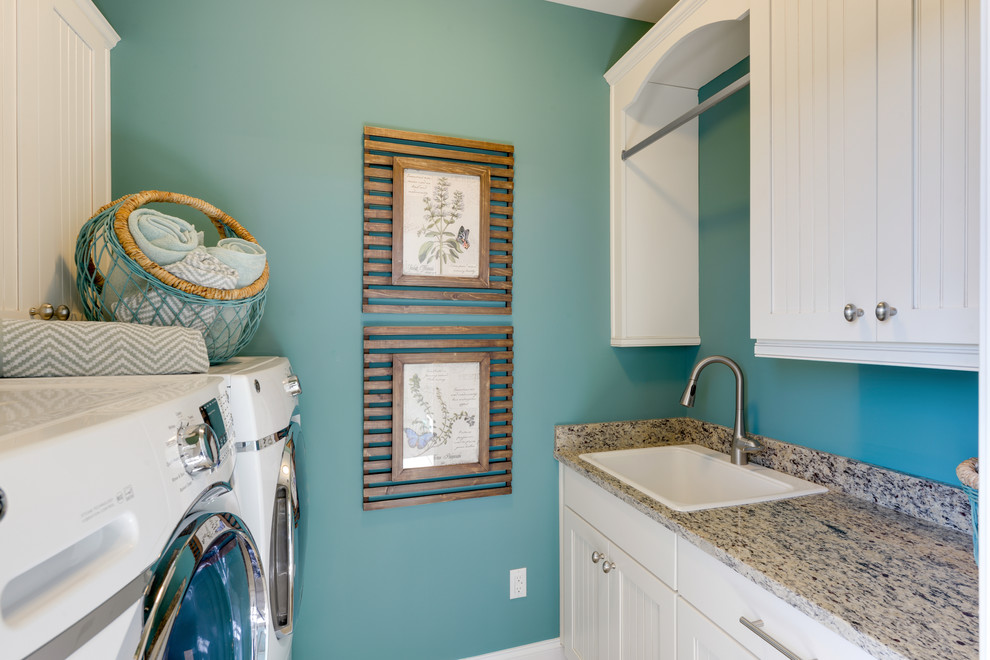 Idee per una sala lavanderia stile marinaro con lavello da incasso, ante bianche, top in granito, pareti blu, lavatrice e asciugatrice affiancate e ante con riquadro incassato