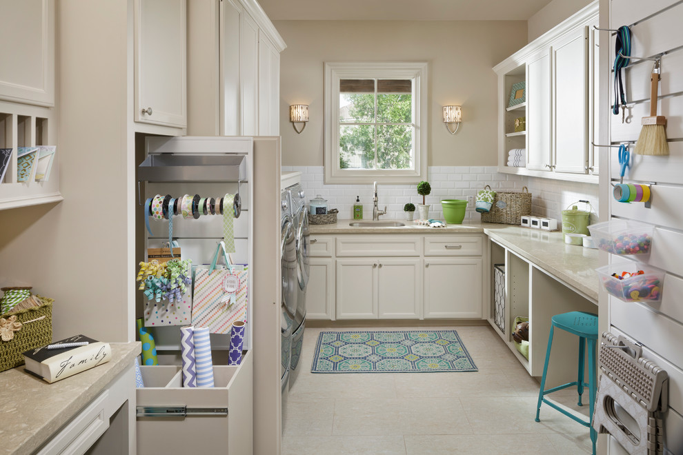 Inspiration for a large timeless u-shaped porcelain tile utility room remodel in Houston with a single-bowl sink, recessed-panel cabinets, white cabinets, limestone countertops, a side-by-side washer/dryer, beige walls and beige countertops