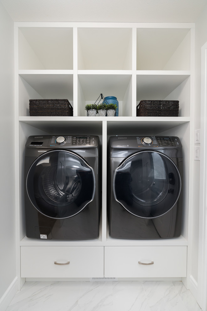 Example of a small minimalist ceramic tile and white floor dedicated laundry room design in Other with white cabinets, white walls and a side-by-side washer/dryer
