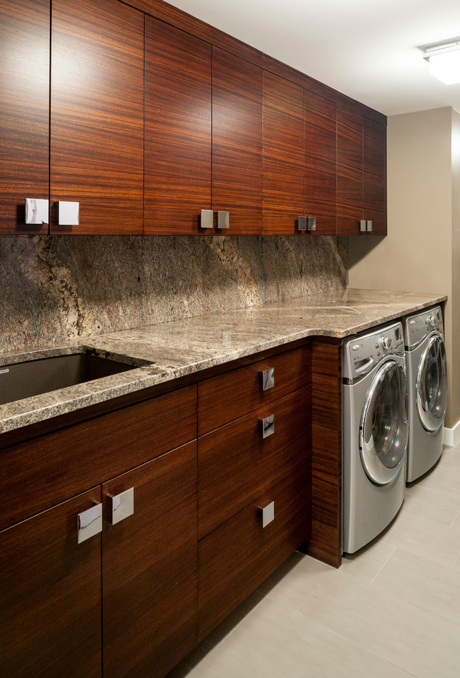 Immagine di una sala lavanderia stile americano di medie dimensioni con lavello sottopiano, ante lisce, ante in legno bruno, top in granito, pareti grigie, pavimento in laminato, lavatrice e asciugatrice affiancate e pavimento grigio