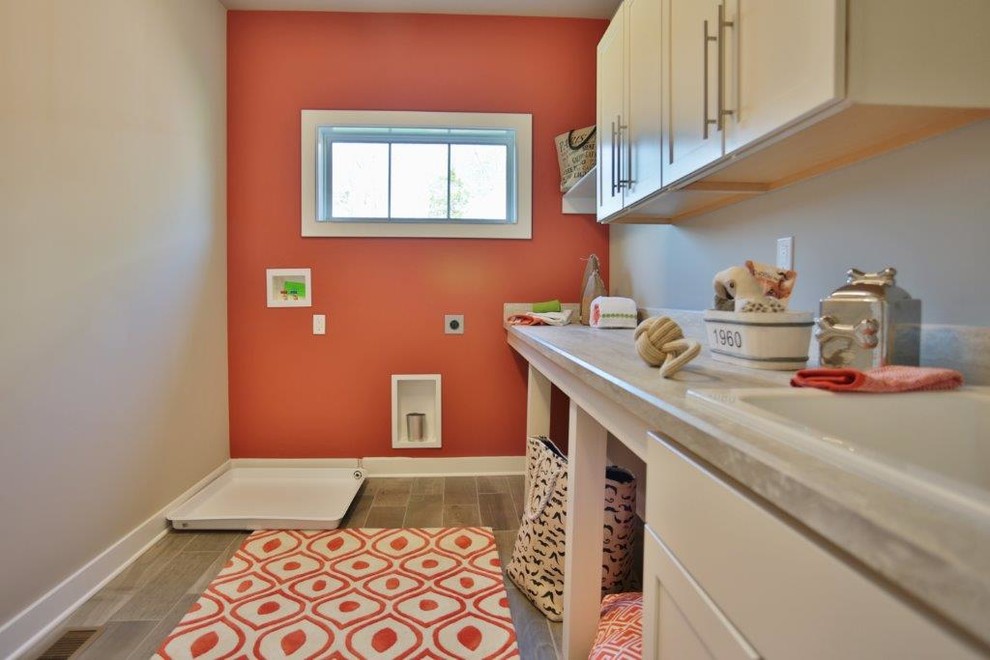ルイビルにある中くらいなトランジショナルスタイルのおしゃれな洗濯室 (ドロップインシンク、シェーカースタイル扉のキャビネット、白いキャビネット、ラミネートカウンター、赤い壁、セラミックタイルの床、左右配置の洗濯機・乾燥機) の写真