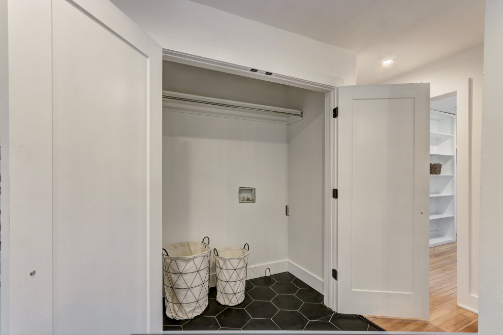 オクラホマシティにあるお手頃価格の小さなトラディショナルスタイルのおしゃれなランドリークローゼット (I型、白い壁、セラミックタイルの床、左右配置の洗濯機・乾燥機、黒い床) の写真