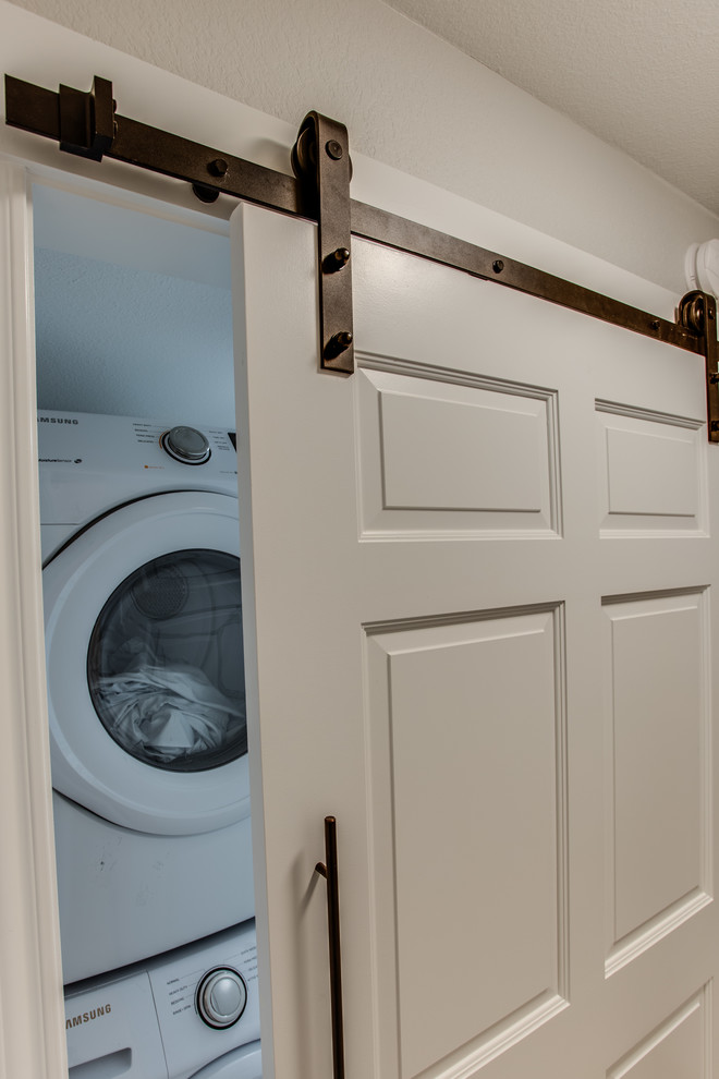 This is an example of a small classic single-wall separated utility room in Austin with engineered stone countertops, porcelain flooring, a stacked washer and dryer and grey floors.