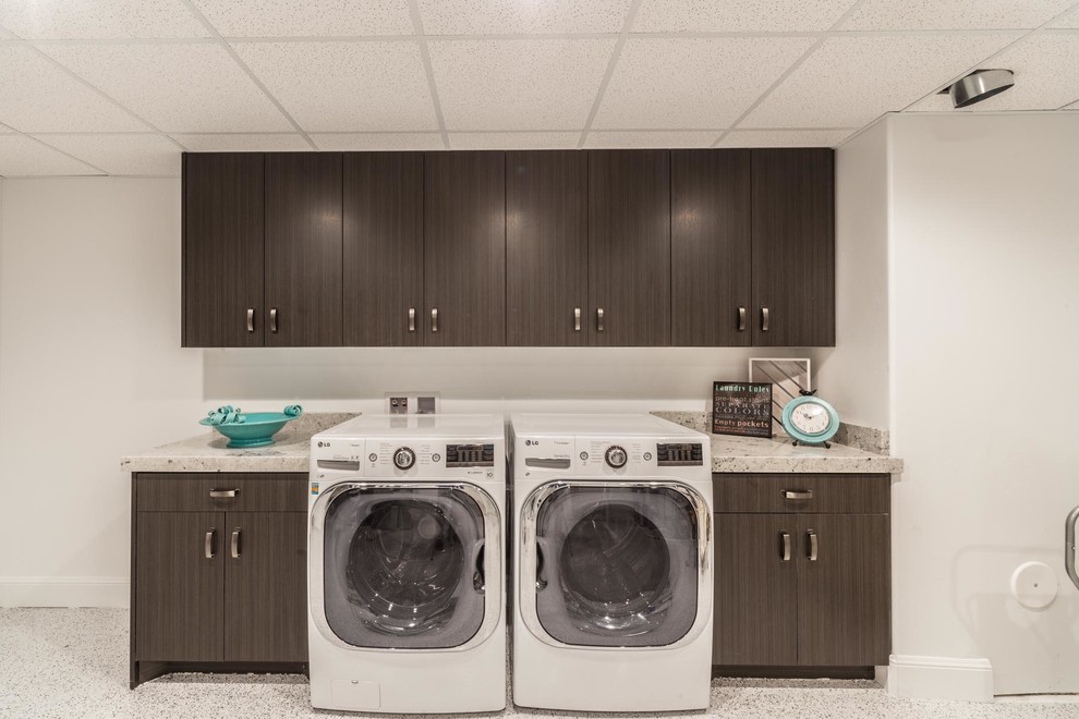 Inspiration för stora klassiska linjära tvättstugor enbart för tvätt, med släta luckor, granitbänkskiva, vita väggar, vinylgolv, en tvättmaskin och torktumlare bredvid varandra, grått golv och skåp i mörkt trä