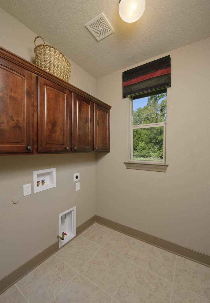 Immagine di una lavanderia classica con ante con bugna sagomata, ante in legno bruno, pareti beige, pavimento in linoleum, lavatrice e asciugatrice affiancate e pavimento beige