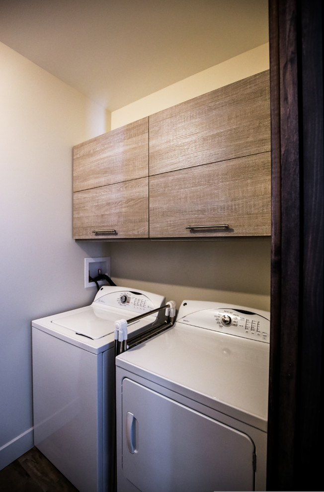 Bild på en mellanstor lantlig parallell tvättstuga enbart för tvätt, med en allbänk, släta luckor, laminatbänkskiva, vita väggar, klinkergolv i porslin, en tvättmaskin och torktumlare bredvid varandra och skåp i mellenmörkt trä