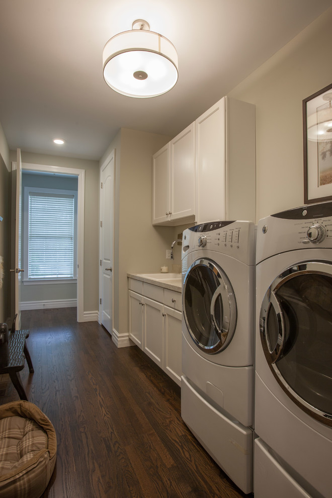 Mid-sized trendy galley medium tone wood floor dedicated laundry room photo in St Louis with flat-panel cabinets, granite countertops, beige walls, a side-by-side washer/dryer, white cabinets and a drop-in sink