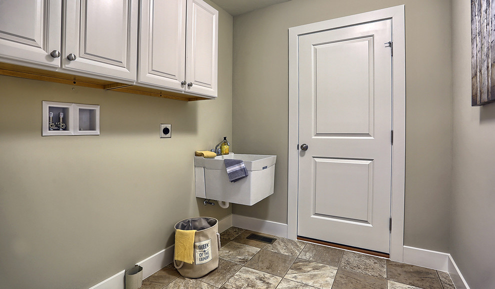 Foto på en mellanstor amerikansk tvättstuga enbart för tvätt, med en allbänk, vita skåp, grå väggar, vinylgolv och en tvättmaskin och torktumlare bredvid varandra