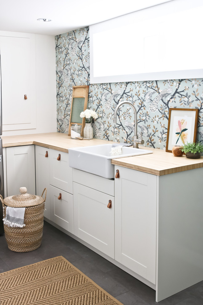 Idee per una lavanderia classica con lavello stile country, ante in stile shaker, ante bianche, top in legno, pavimento grigio e top beige