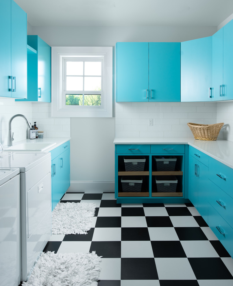 Klassische Waschküche mit Einbauwaschbecken, flächenbündigen Schrankfronten, weißer Wandfarbe, Waschmaschine und Trockner nebeneinander, buntem Boden, weißer Arbeitsplatte, Vinylboden und blauen Schränken in Boise