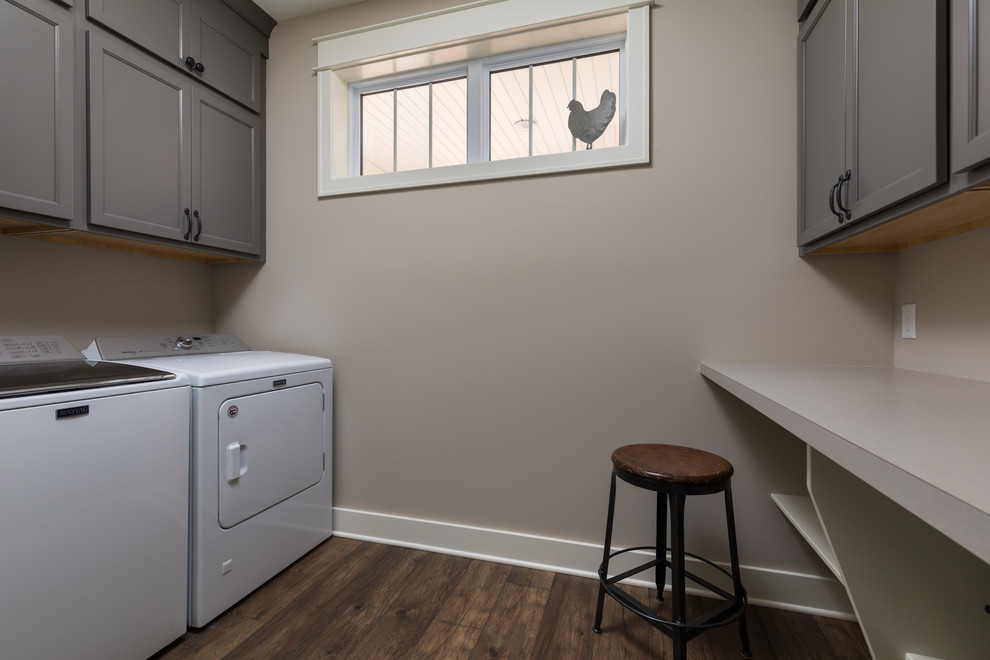 Foto de cuarto de lavado de galera tradicional de tamaño medio con armarios con paneles empotrados, puertas de armario grises, encimera de laminado, suelo laminado y suelo marrón