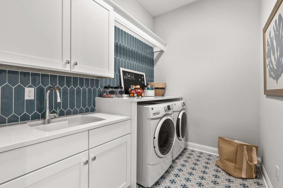 Immagine di una sala lavanderia country di medie dimensioni con lavello a doppia vasca, ante a filo, ante bianche, pareti grigie, lavatrice e asciugatrice affiancate e top bianco