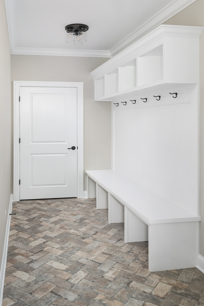 Immagine di una sala lavanderia country di medie dimensioni con ante bianche e pavimento in mattoni