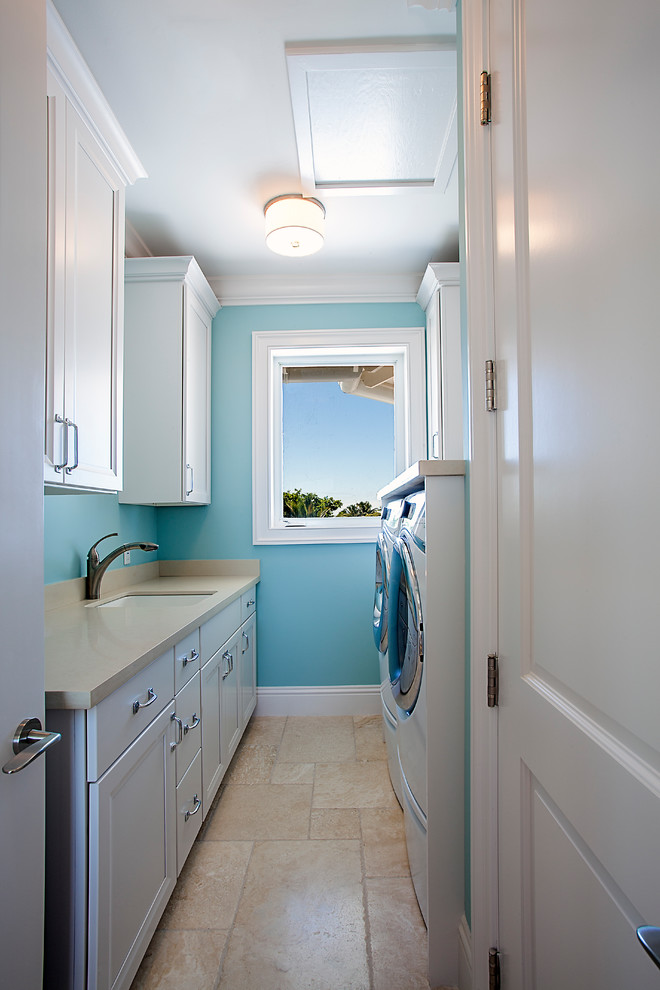 Foto di una grande sala lavanderia stile marino con lavello da incasso, ante con riquadro incassato, ante bianche, top in superficie solida, pareti blu, pavimento con piastrelle in ceramica, lavatrice e asciugatrice affiancate e pavimento beige