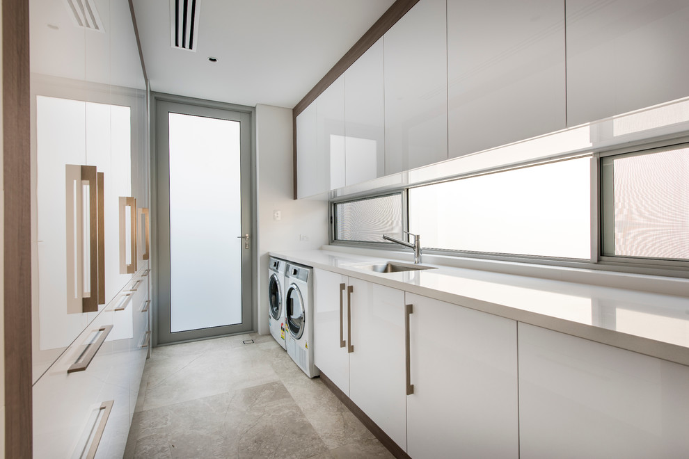 Immagine di una sala lavanderia design con lavatrice e asciugatrice affiancate
