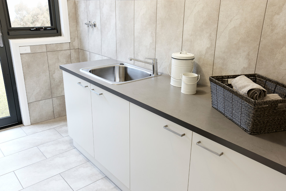 Exempel på en liten modern parallell tvättstuga enbart för tvätt, med en enkel diskho, släta luckor, beige skåp, laminatbänkskiva, beige väggar och klinkergolv i keramik