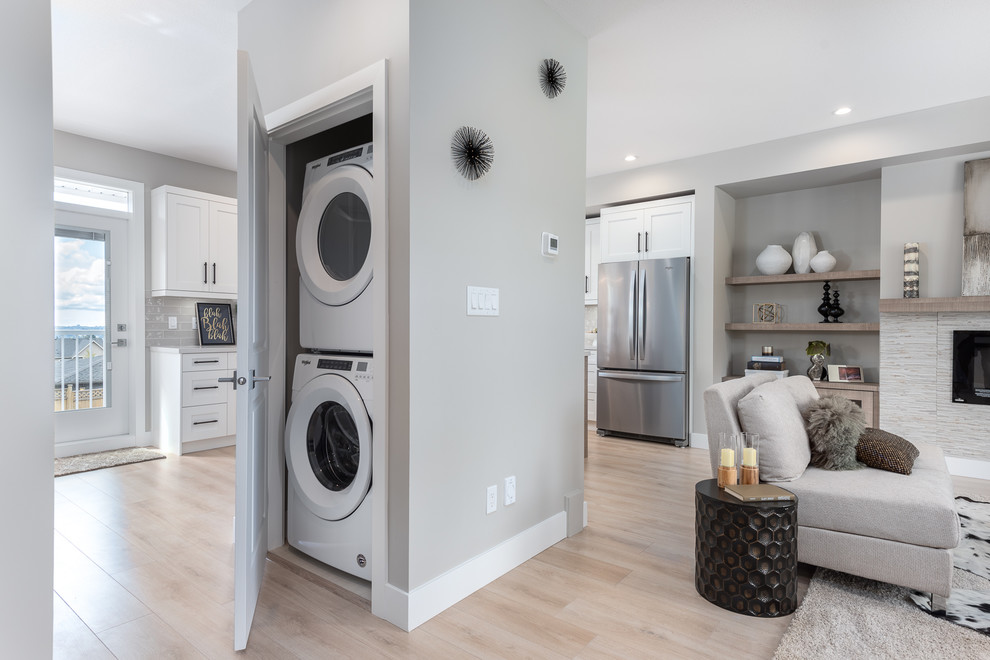 Immagine di un piccolo ripostiglio-lavanderia stile americano con pareti grigie, pavimento in laminato, lavatrice e asciugatrice a colonna e pavimento beige