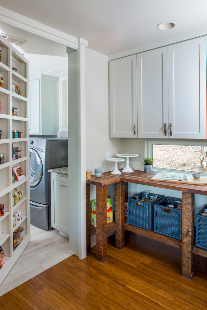Utility room - mid-sized transitional single-wall medium tone wood floor and brown floor utility room idea in Austin with shaker cabinets, white cabinets, wood countertops, white walls and a side-by-side washer/dryer