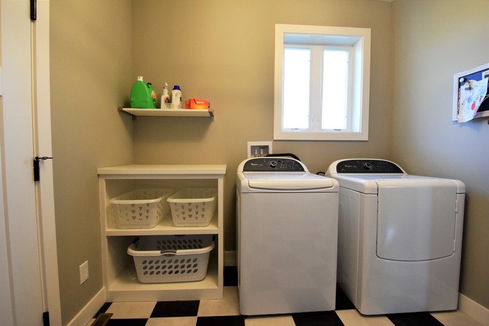 Exempel på en mellanstor amerikansk linjär tvättstuga enbart för tvätt, med öppna hyllor, vita skåp, träbänkskiva, grå väggar, en tvättmaskin och torktumlare bredvid varandra och flerfärgat golv
