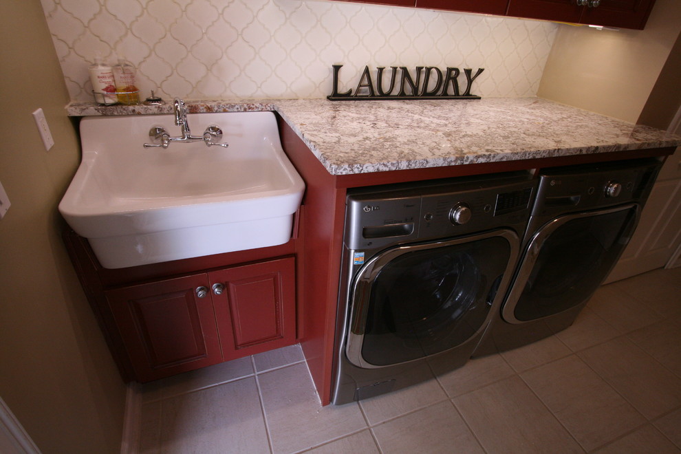Immagine di una lavanderia country con ante con bugna sagomata, ante in legno bruno e lavatrice e asciugatrice affiancate