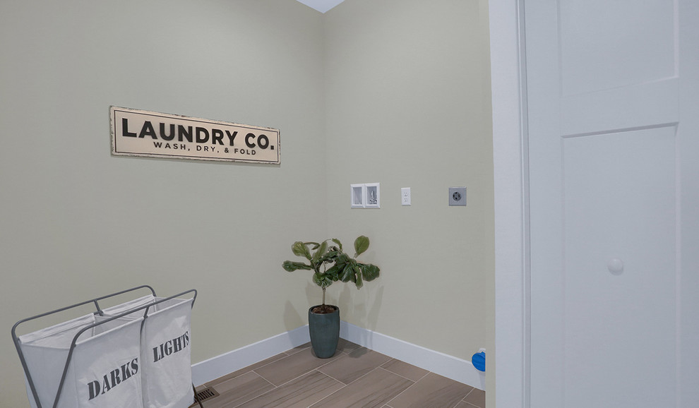 Foto di una grande sala lavanderia chic con pareti grigie, pavimento con piastrelle in ceramica, lavatrice e asciugatrice affiancate e pavimento marrone