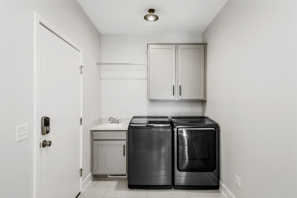 Foto på en mellanstor vita linjär liten tvättstuga, med en nedsänkt diskho, skåp i shakerstil, grå skåp, grå väggar, klinkergolv i keramik, en tvättmaskin och torktumlare bredvid varandra och vitt golv