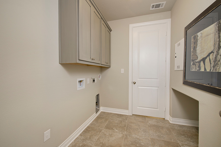Cette image montre une petite buanderie traditionnelle avec un placard, un placard à porte shaker, des portes de placard grises, un mur gris, un sol en carrelage de céramique et un sol beige.