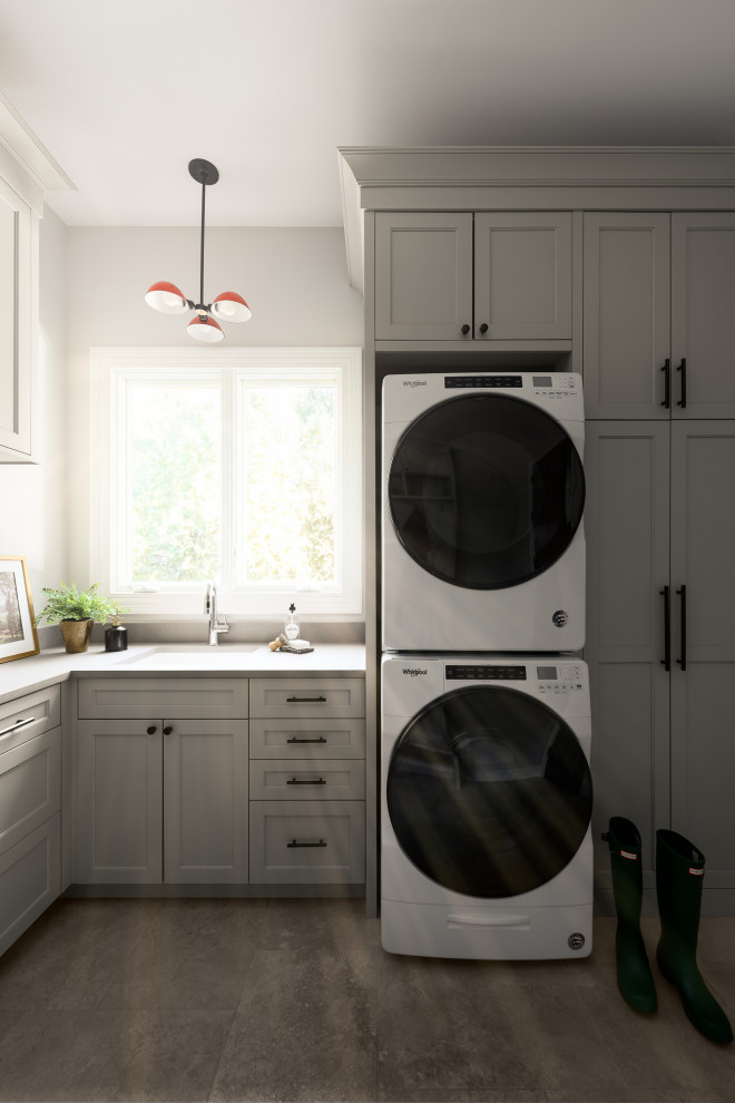 Exempel på en stor klassisk grå u-formad grått tvättstuga enbart för tvätt, med en undermonterad diskho, släta luckor, beige skåp, granitbänkskiva, vita väggar, travertin golv, en tvättpelare och grått golv